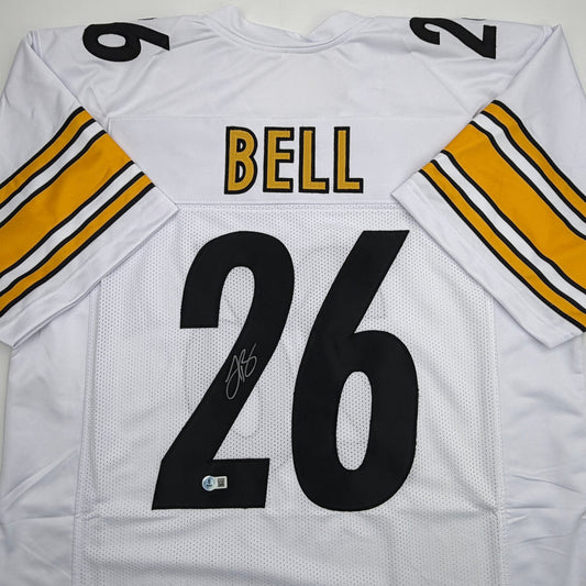 White Pittsburgh Steelers jersey displayed flat showing back with "BELL" nameplate, number 26, autographed, gold and black striped sleeves visible.