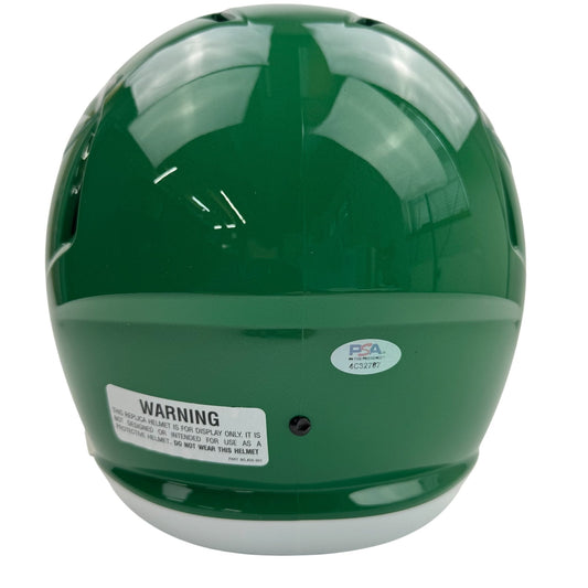 Rear view of green football helmet with white warning label and PSA authentication sticker visible on back.