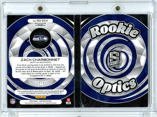 Front and back of 2023 Panini Spectra Zach Charbonnet rookie card in clear case, showing Seattle Seahawks logo and blue Spectra Optics design.