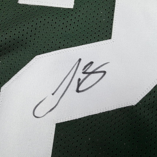 Close-up of autographed white fabric label on green perforated jersey showing "Le'Veon" handwritten signature in black ink.