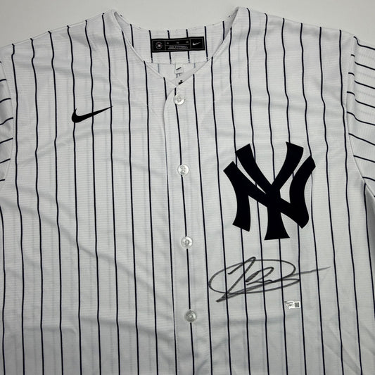 White pinstriped Yankees jersey with black NY logo and autographed signature visible on front chest area.
