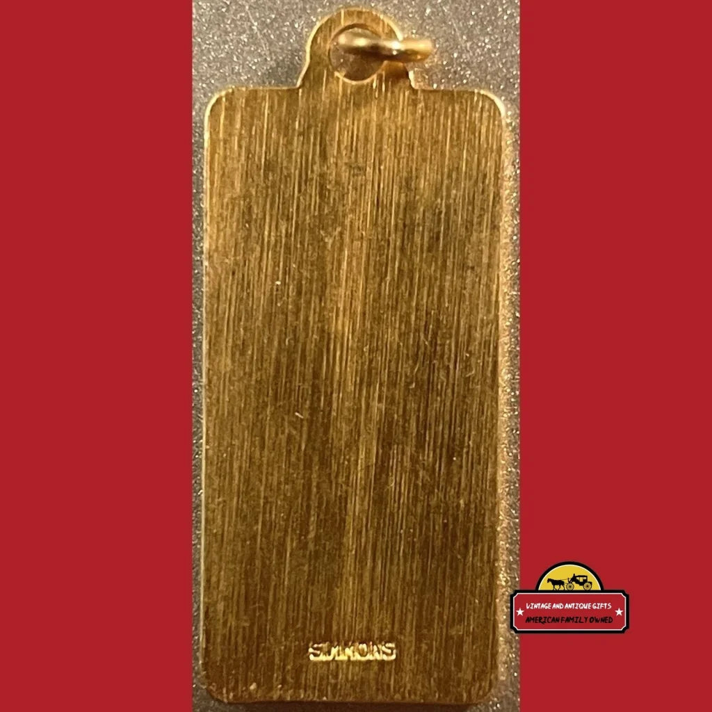 Golden rectangular pendant with brushed texture atop Vintage 1970s keychain fobs