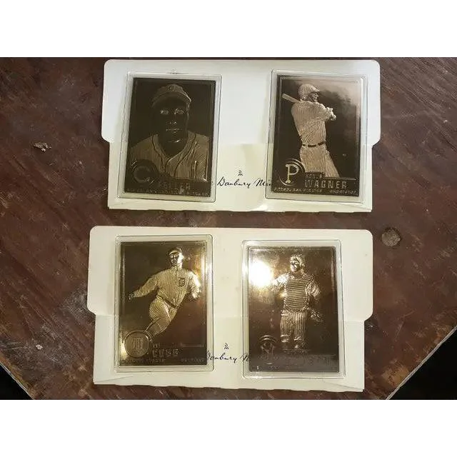 Four 22kt gold baseball cards featuring Honus Wagner and Ty Cobb in protective sleeves