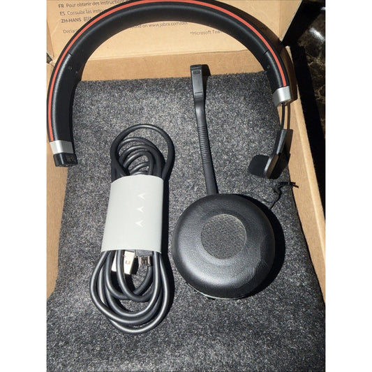 Jabra Evolve 65 SE headset displayed flat with coiled cable, boom microphone, and ear cup on gray foam padding.