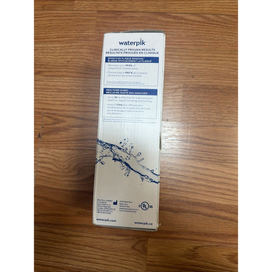 Waterpik product box rear view on wooden floor showing clinically proven results text and water splash graphic in blue and white.