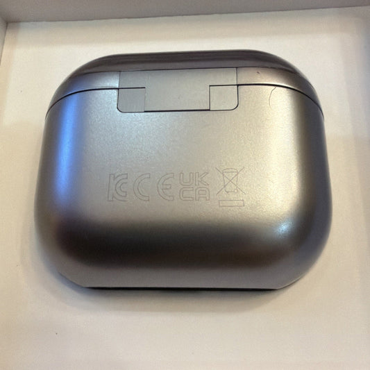 Silver Samsung Galaxy Buds3 charging case viewed from above, showing rounded rectangular metallic surface with regulatory markings and hinged lid.