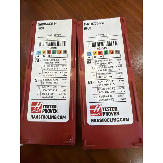 Two red Haas carbide insert packages with white specification labels displayed side-by-side on brown surface.