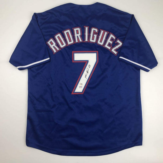 Back view of a blue baseball jersey with arched RODRIGUEZ lettering, a white number 7, and a black signature.