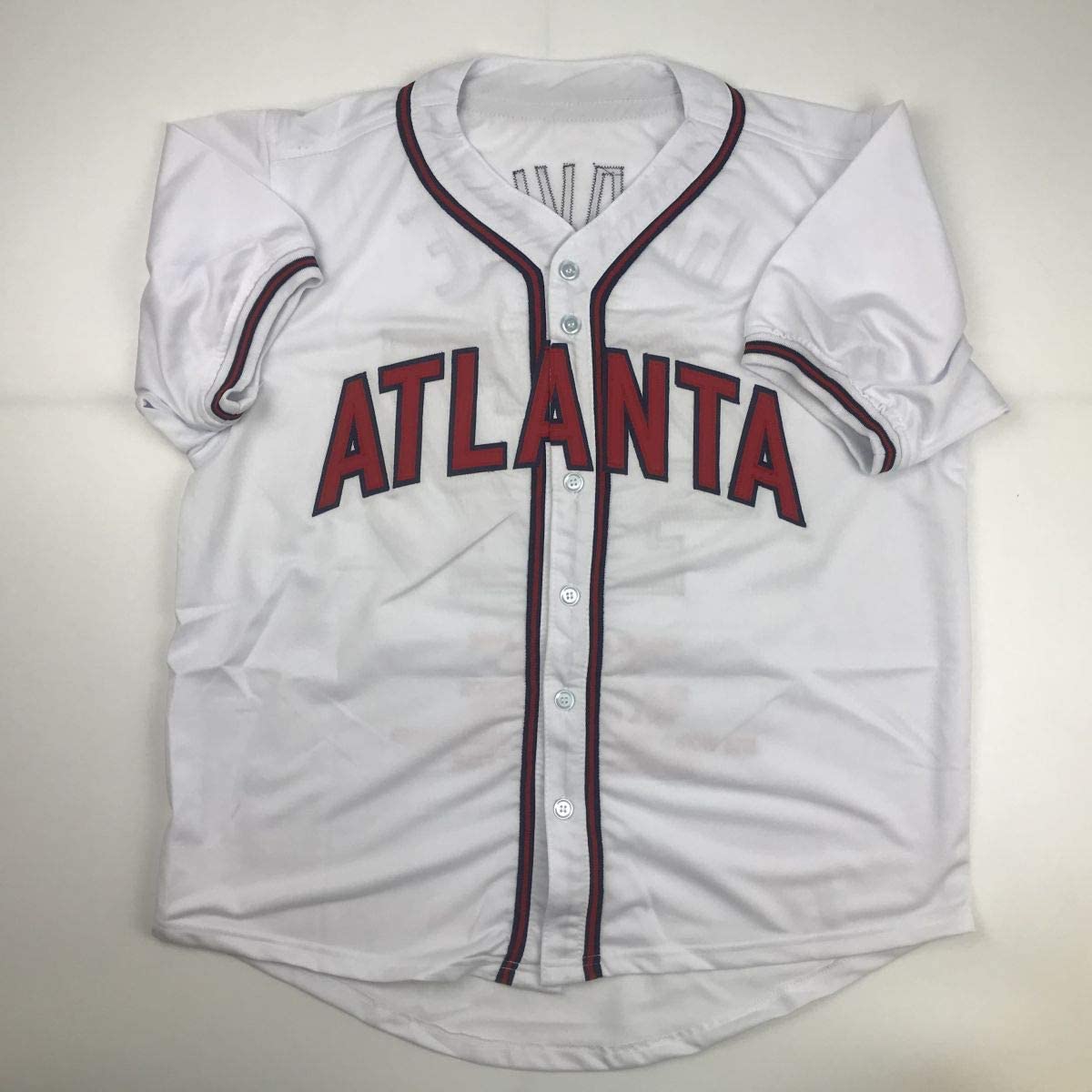 White Atlanta Braves baseball jersey with red lettering and maroon piping, displayed flat against neutral background.