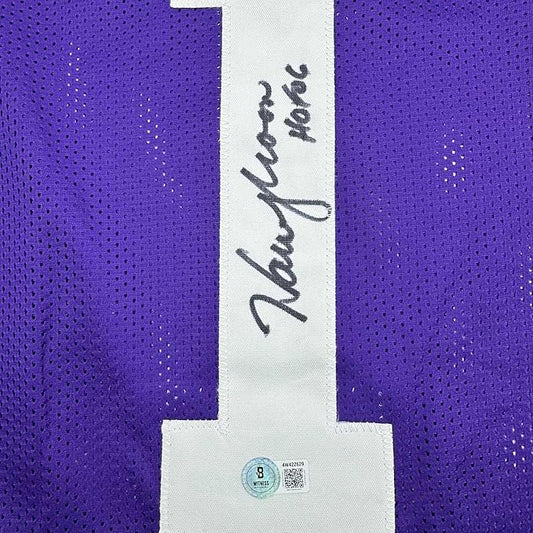 Close-up of purple mesh jersey back showing white vertical stripe with "Warren Moon" handwritten signature and authentication label.