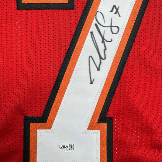 Close-up of autographed white stripe on red Tampa Bay football jersey with black handwritten signature and JSA authentication label.