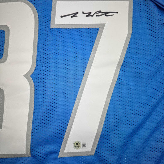 Close-up of blue mesh football jersey with white stripe and handwritten signature at top, showing fabric texture and Beckett authentication label at bottom.
