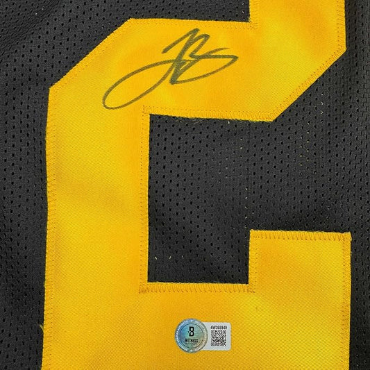 Close-up of yellow mesh football jersey with black stripe, showing autographed signature and JSA authentication hologram sticker.