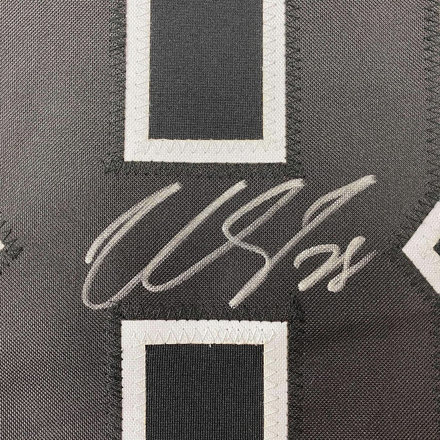 Close-up of Claude Giroux's silver autograph on black hockey jersey with white fabric borders visible.