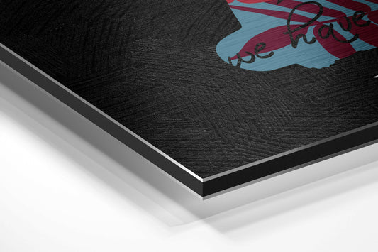 Close-up angled view of layered Dibond wall art showing black brushed aluminum surface with red and blue collage design and text detail.