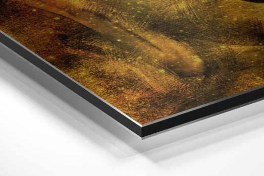 Close-up angled view of layered aluminium dibond print showing gold and brown textured Buddha face with black and silver mounting edges against white background.