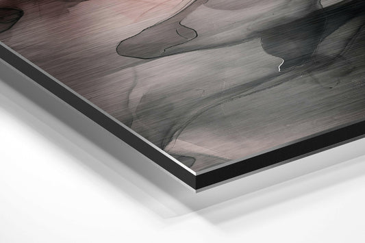 Close-up angled view of layered Dibond framing showing brushed aluminum surface with blush pink and gray cloud abstract pattern and black border edge.