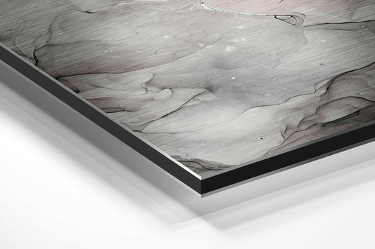 Close-up angled view of framed marble wall art showing white and pink veined surface with black aluminum border and mounting layers.