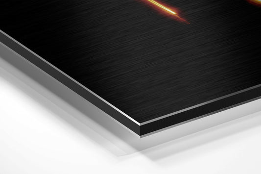 Angled perspective view of layered brushed aluminum composite material with black top surface and white base, gold light streak visible at top.