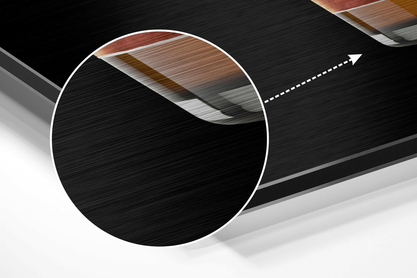 Close-up detail of brushed aluminium surface showing wood grain texture and layered edge construction with magnifying circle overlay.