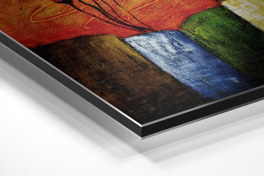 Angled close-up of layered aluminum dibond print showing vibrant red, brown, blue, and green color blocks with brushed metallic finish and black border.