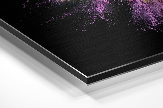 Angled perspective view of layered Dibond wall art with black brushed aluminum surface and purple powder explosion design, white backing visible.