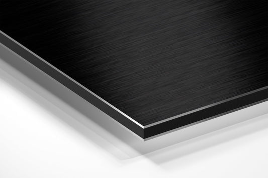 Close-up angled view of layered composite material showing black brushed aluminum top surface with white and gray backing layers.