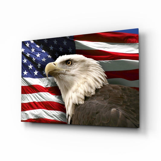 Bald eagle with white head and brown body positioned in front of rippling American flag on glass wall art panel.