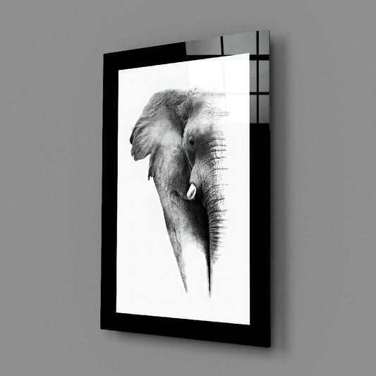 Framed charcoal sketch of an elephant's head in profile mounted on a gray wall, displayed at an angle showing the black frame and glass surface.