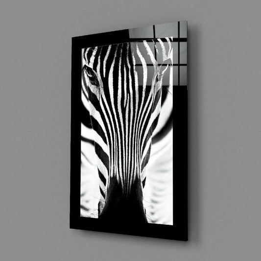 Black-framed glass wall art displaying a close-up black and white zebra head facing forward, mounted on gray wall.
