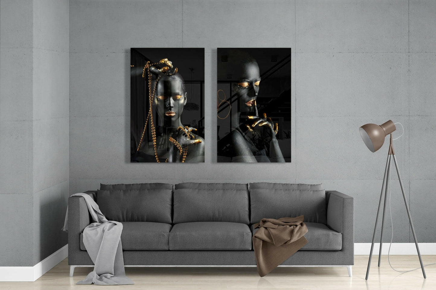 Two black and gold portrait glass panels mounted above gray sofa in minimalist room interior.
