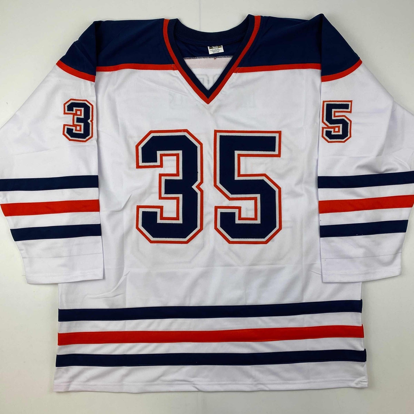 White Edmonton Oilers hockey jersey with navy and red stripes, number 35 in navy and red lettering, displayed flat against white background.