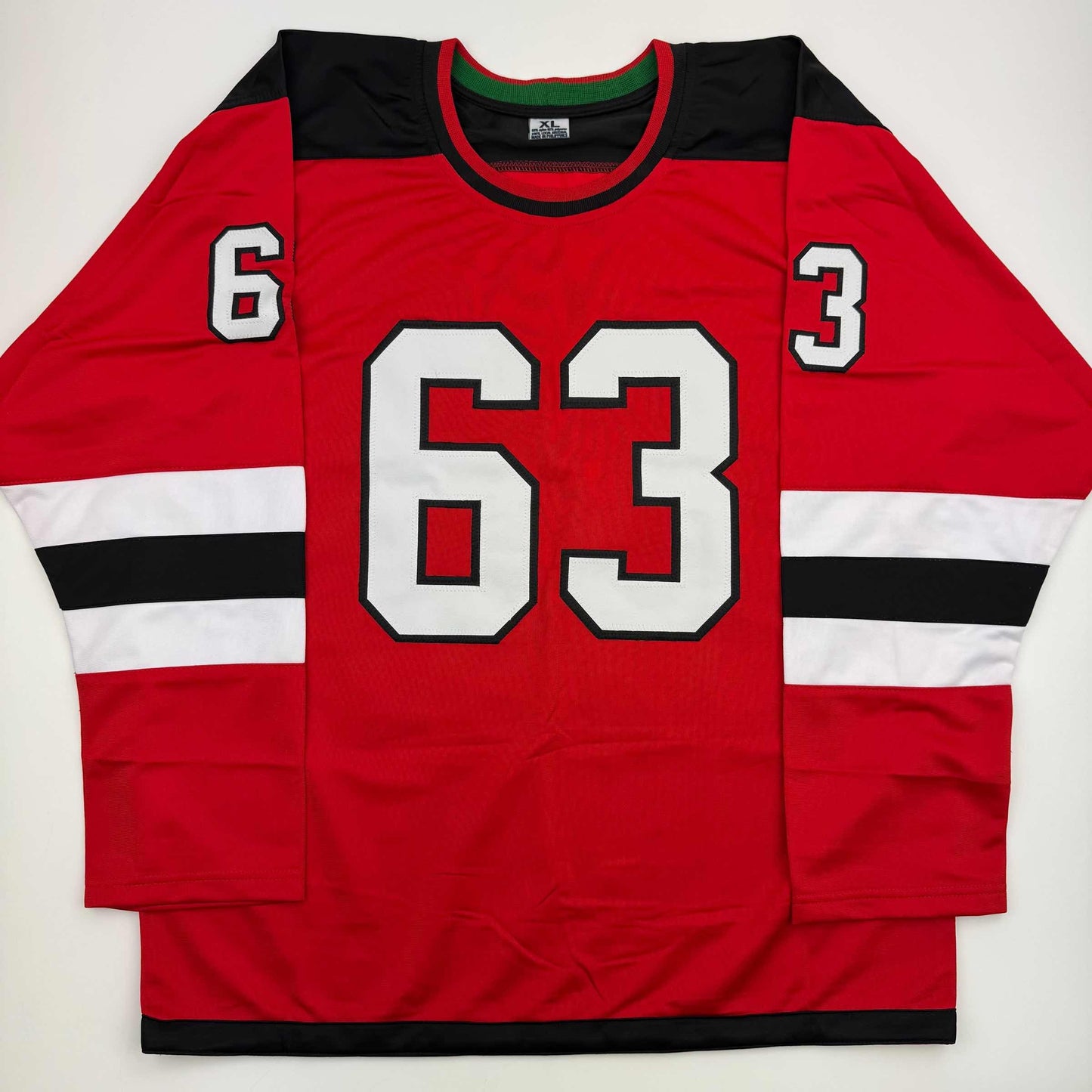 Red hockey jersey with black and white striping, displaying white number 63 on chest and smaller numbers 6 and 3 on shoulders, flat lay view.