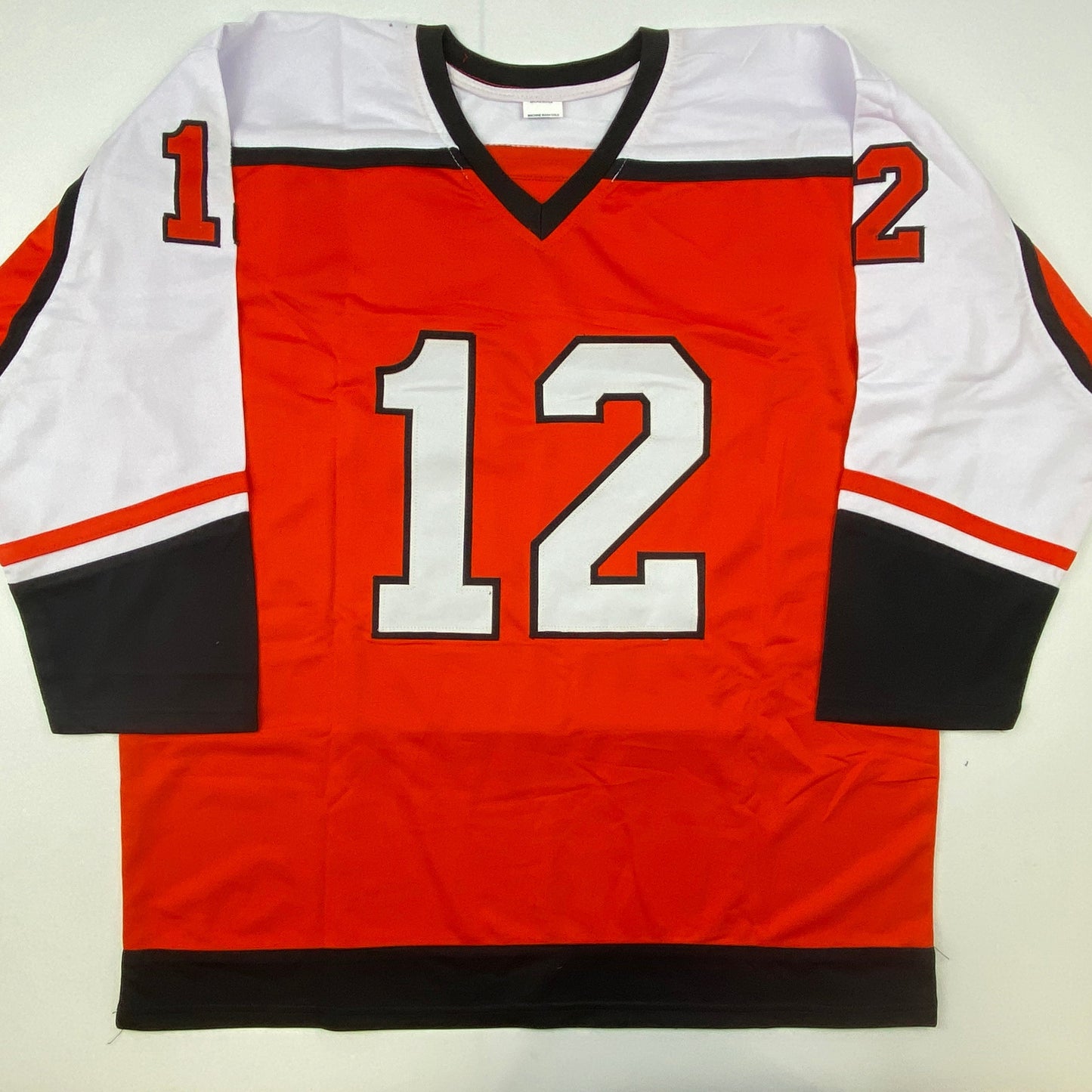 Red, white, and black hockey jersey with number 12 displayed flat against white background, front view.