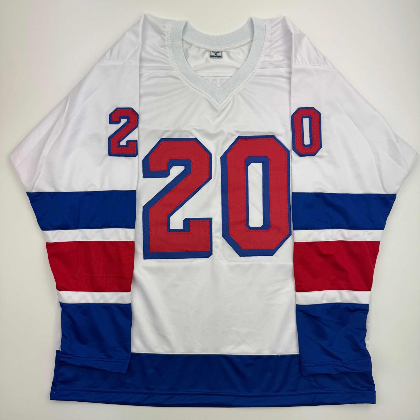 White hockey jersey with red and blue horizontal stripes, displaying number 20 in red with blue outline on front and shoulders.