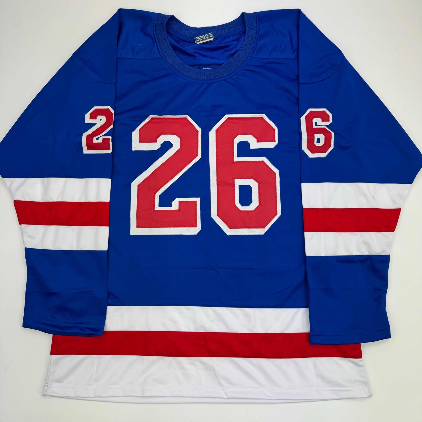 Blue hockey jersey with red and white horizontal stripes, large red number 26 on chest, displayed flat against white background.