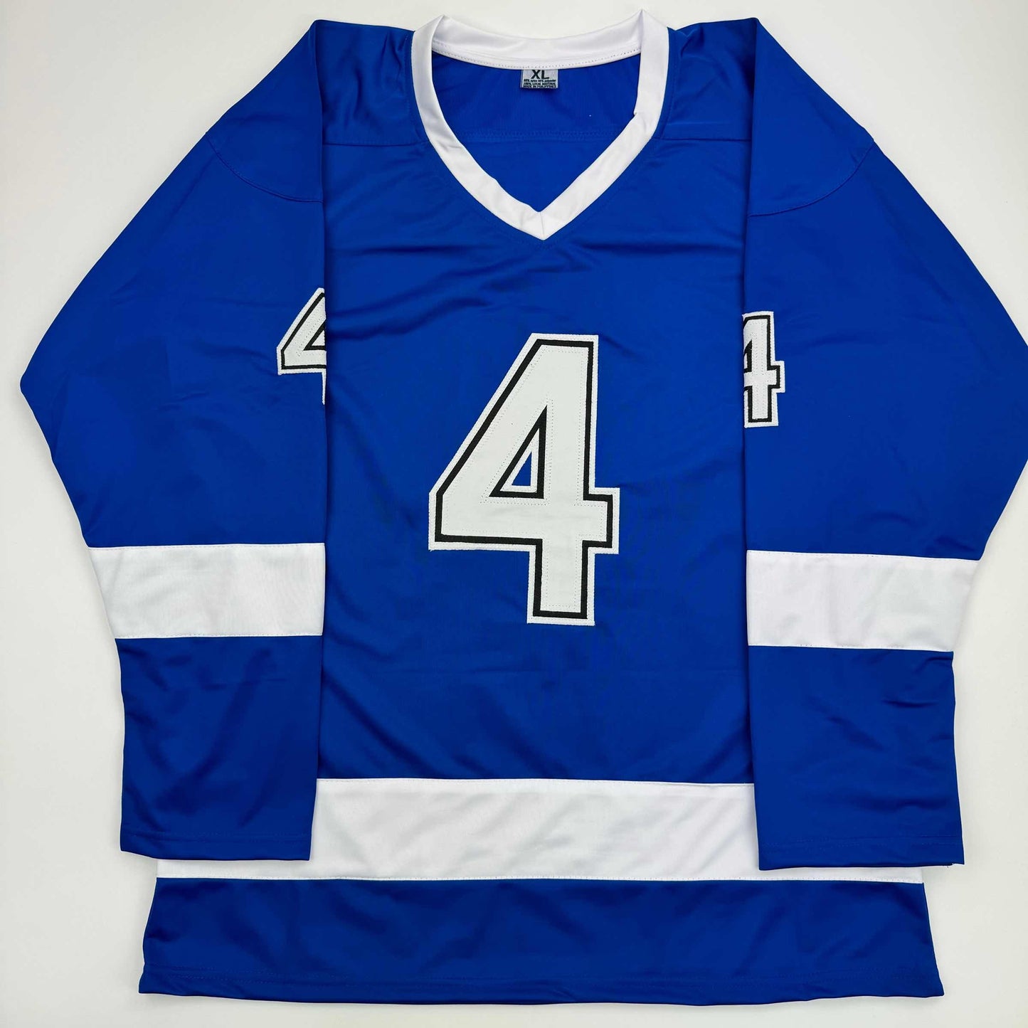 Blue hockey jersey with white trim and number 4 displayed flat on white background, front view.