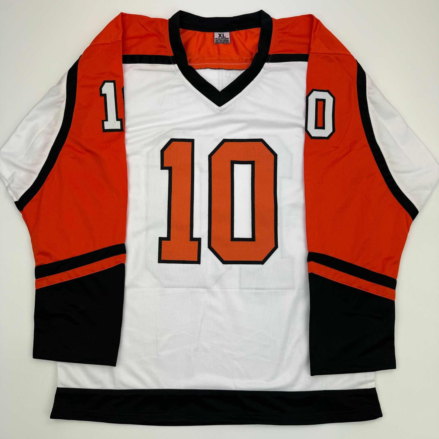White hockey jersey with orange and black trim, number 10 in orange on chest, displayed flat against gray background.