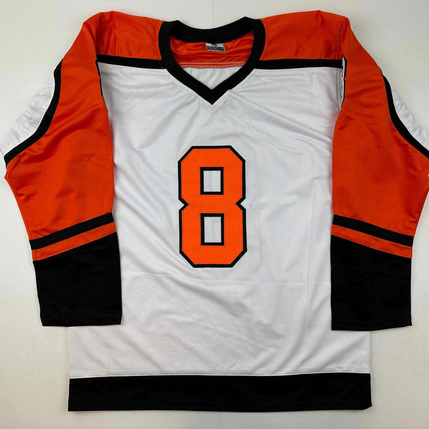 White hockey jersey with orange and black trim, number 8 in orange with black outline, displayed flat against neutral background.