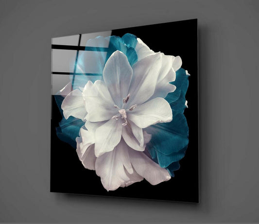 Angled perspective view of layered glass wall art displaying white and teal tulip flower against black background with visible frame edges.