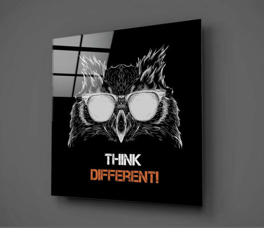 Black glass wall art panel displaying an owl wearing oversized sunglasses with "THINK DIFFERENT!" text, shown at an angle against gray wall.