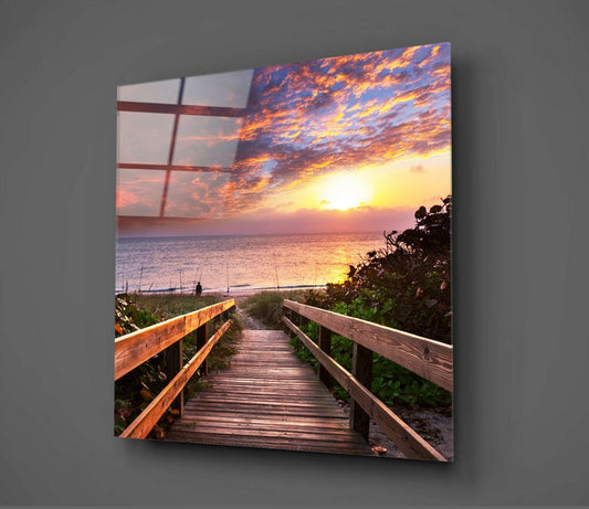 Wooden boardwalk leading toward ocean at sunset displayed as glass wall art with window frame overlay on gray background.
