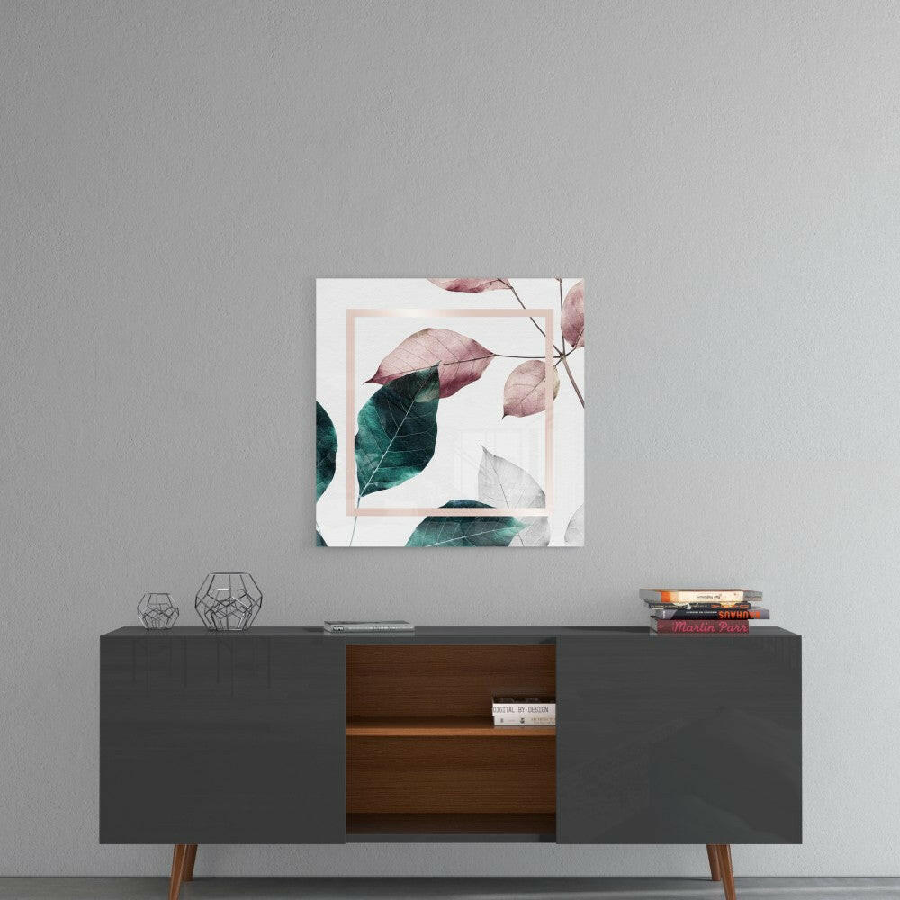 Square glass wall art with watercolor leaves in pink, teal, and green tones with peach frame, displayed above mid-century modern console table.