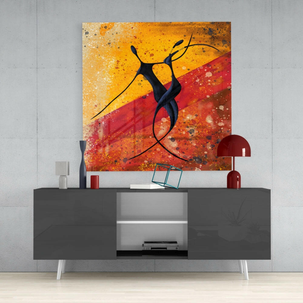 Glass wall art featuring abstract black figure against orange and red gradient background with splatter texture, displayed above gray console table.