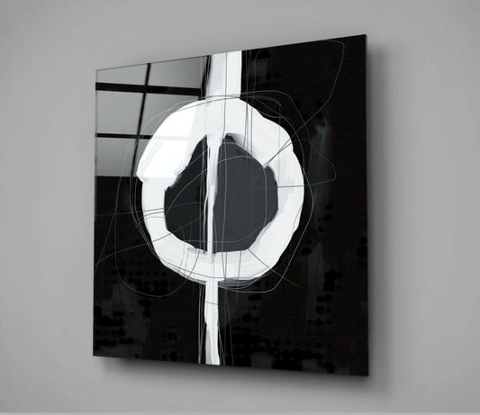 Modern black glass wall art panel featuring a white Enso circle with geometric line overlay, mounted at an angle against gray wall.