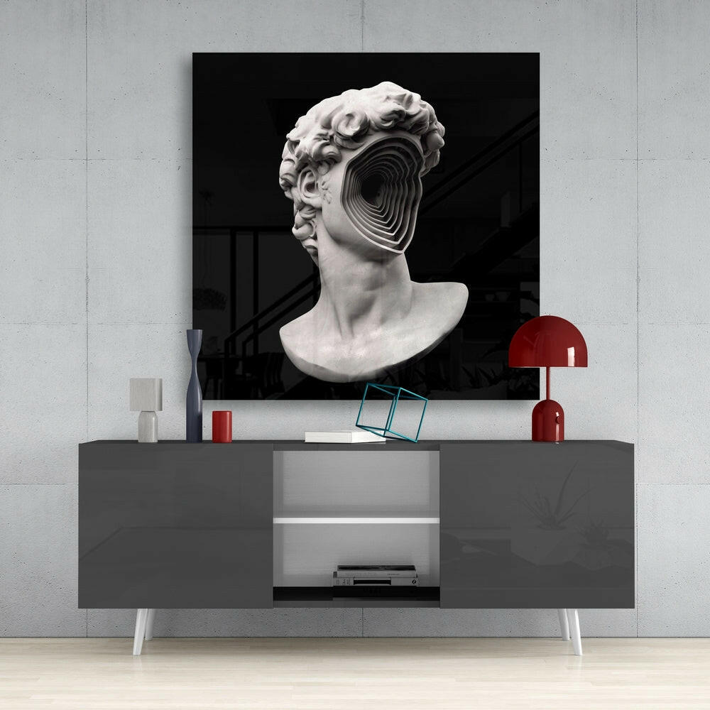 White plaster classical bust with concentric circular glass inlay on dark background, displayed above gray modern console table with red accents.