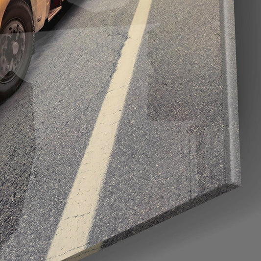 Close-up of asphalt road surface with white center line and truck tire visible in upper left corner.