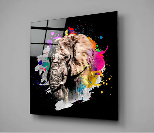 Black glass wall art displaying a split elephant head design with detailed line work on left side and vibrant paint splashes in magenta, yellow, blue, and orange on right side, mounted at angle against gray wall.