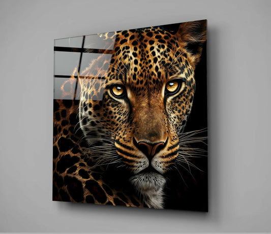Square glass wall art displaying a close-up leopard face with golden eyes and spotted coat against black background, mounted on gray wall.