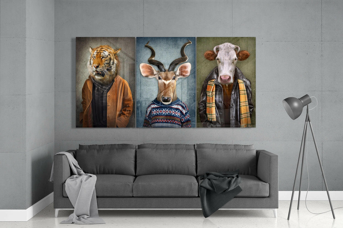 Three glass wall art panels above gray sofa depicting anthropomorphic tiger, antelope, and cow in casual clothing.